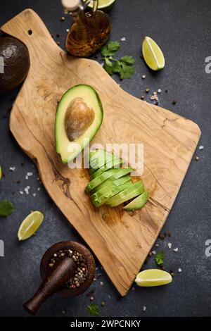 Halbierte grüne Avocadofrucht auf hölzernem Schneidebrett in der Hausküche Stockfoto