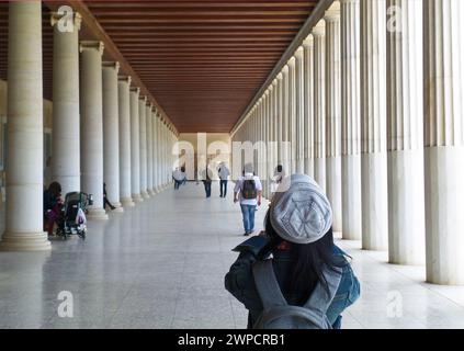 Besucher in einem Korridor mit Reihen massiver Säulen von Stoa of Attalos, Museum der antiken Agora in Athen, Griechenland Stockfoto