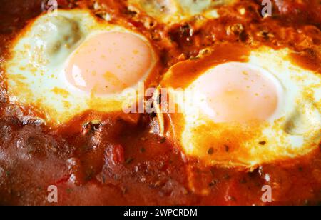 Nahaufnahme von Eiern, die in gewürzter Tomatensauce für Shakshuka pochiert wurden Stockfoto