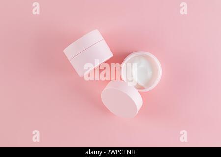 Zwei Kosmetikgläser mit Creme für umfassende Selbstpflege. Tag, Nachtcreme auf rosa Hintergrund. Verpackung leeres Modell der Dose. Öffnen Sie den Becher. Draufsicht Stockfoto