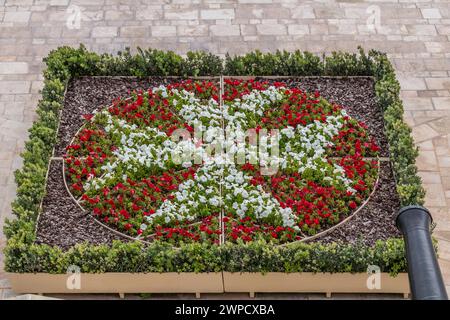 Ein Blumenbeet mit bunten Blumen stellt das maltesische Kreuz, Valletta, Malta dar Stockfoto