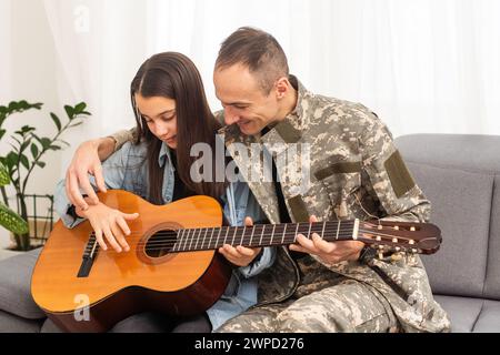 Ein Veteran und seine Tochter spielen Gitarre Stockfoto