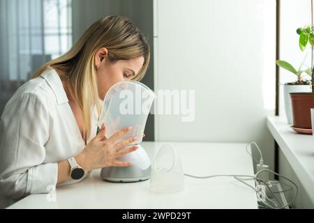 Frau hat eine schlimme Erkältung und versucht eine Therapie mit einem Inhalator Stockfoto