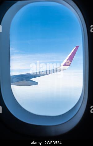 Blick durch das Flugzeugfenster. Fenstersitz in einem Vistara-Flugzeug. Skyscape mit Wolke aus dem Flugzeugfenster. Fliegen und Reisen, Blick aus der Luft Stockfoto