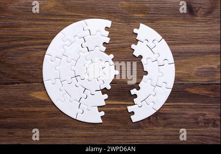 Weißes, kreisförmiges Puzzle auf hölzernem Hintergrund. Stockfoto