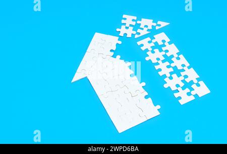 Nahaufnahme einer zerlegten Wohnhausform aus weißen Puzzleteilen isoliert auf blauem Hintergrund. Stockfoto