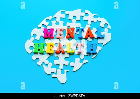 Aufgelöstes, hirnförmiges Puzzle mit den Worten „Mental Health“ in bunten Holzbuchstaben oben. Stockfoto