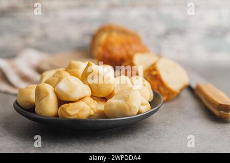 Geräucherter Mini-Scamorza-Käse. Traditioneller italienischer Käse auf dem Teller auf dem Küchentisch. Stockfoto