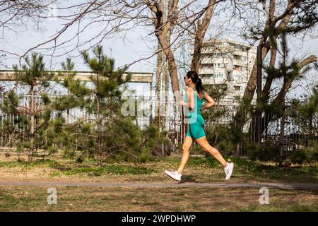 Fit gut aussehendes Mädchen Jogging im grünen Park am Morgen, gesundes sportliches Leben, aktiv bleiben Stockfoto