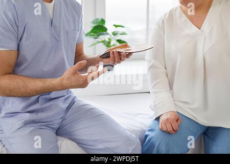 Der Arzt berät den Patienten über individuelle orthopädische Einlagen zur Korrektur von Plattfüßen. Stockfoto