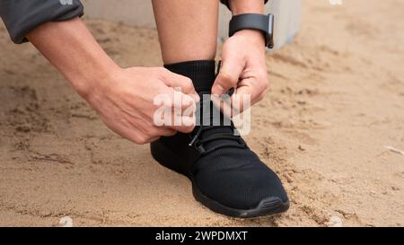 Unerkennbarer junger kaukasischer Mann schnürt seine Turnschuhe vor dem Training. Stockfoto