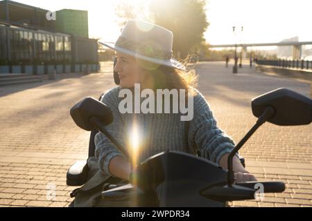 Frau, die auf einer Straße in der Stadt einen Elektroroller mit vier Rädern fährt. Stockfoto