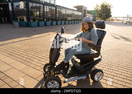 Frau, die auf einer Straße in der Stadt einen Elektroroller mit vier Rädern fährt. Stockfoto