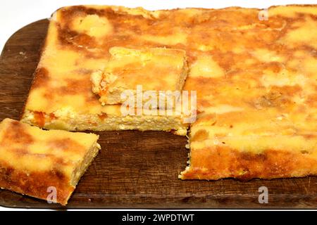 Das Bild zeigt einen Auflauf aus Hüttenkäse und Kürbis. Aus dem Auflauf wurde ein Stück geschnitten. Stockfoto