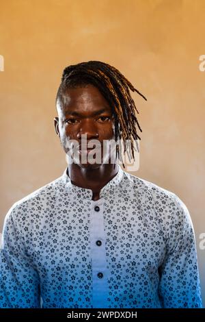 Studio-Porträt eines selbstbewussten afrikanischen Mannes mit stilvollen Dreadlocks, die ein Hemd mit Blumenmuster tragen und Eleganz und kulturelle Identität ausstrahlen Stockfoto