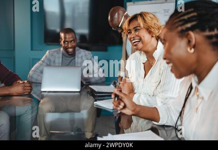 Eine Gruppe von Fachleuten in einem Büro hat ein erfolgreiches Geschäftstreffen. Sie diskutieren, lachen und zeigen eine fröhliche Teamatmosphäre im Sitzungssaal. Stockfoto