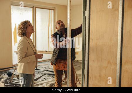 Bauarbeiter und Hausarchitekt diskutieren über Pläne zur Innenumgestaltung. Sie arbeiten an einem Renovierungsprojekt für ein Haus mit Schwerpunkt auf Redesi Stockfoto