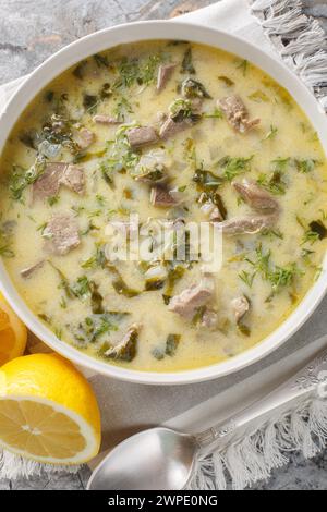 Griechische Ostersuppe Magiritsa mit Lammabfällen, Kräutern, mit Ei und Zitronensauce in einer Schüssel auf einem Marmortisch. Vertikale Draufsicht von abo Stockfoto