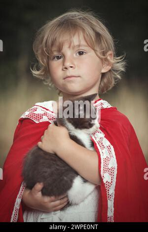 Rotkäppchen mit Futterkorb, der mit Kätzchen im Wald posiert Stockfoto