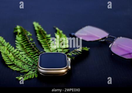 Besagter Blick auf stilvolle Smart-Uhr und Sonnenglas. Mit schwarzem Hintergrund Stockfoto