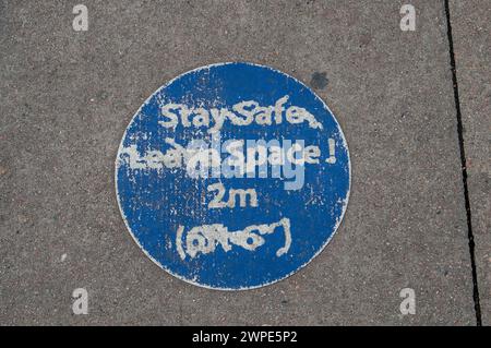 London, Großbritannien. März 2024. Ein altes COVID-19-Zeichen für soziale Distanzierung auf einem Bürgersteig in London. Kredit: Maureen McLean/Alamy Stockfoto