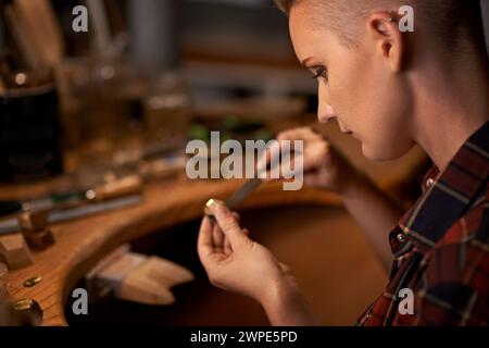 Holzbearbeitung, Werkzeuge und Künstler in Werkstatt mit kreativem Projekt oder Skulptur auf dem Tisch bei Nacht. Handwerker, Zimmermann und Frau mit Talent für Stockfoto
