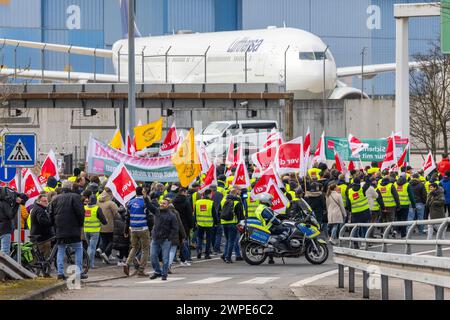 07. März 2024, Hessen, Frankfurt/Main: Ein protestmarsch der Streikenden marschiert mit Bannern und Verdi-Fahnen zum Lufthansa Aviation Center. Im Hintergrund ist ein Flugzeug der Lufthansa zu sehen. Mit erneuten Warnstreiks mehrerer Berufsgruppen lähmt die Verdi union am Donnerstag und Freitag wichtige Teile des deutschen Luftverkehrs. Foto: Lando Hass/dpa Stockfoto