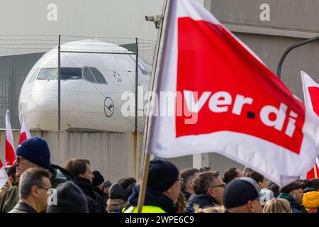 07. März 2024, Hessen, Frankfurt/Main: Protestprozession von Streikenden marschiert mit Bannern und Verdi-Fahnen zum Lufthansa Aviation Center. Im Hintergrund ist ein Flugzeug der Lufthansa zu sehen. Mit erneuten Warnstreiks mehrerer Berufsgruppen lähmt die Verdi union am Donnerstag und Freitag wichtige Teile des deutschen Luftverkehrs. Foto: Lando Hass/dpa Stockfoto