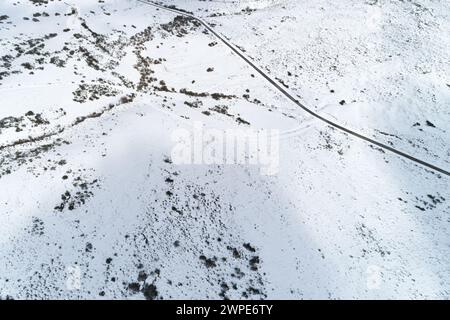 Drohnenblick auf eine Straße in einem verschneiten Berg, Transport im Winter Konzept Stockfoto