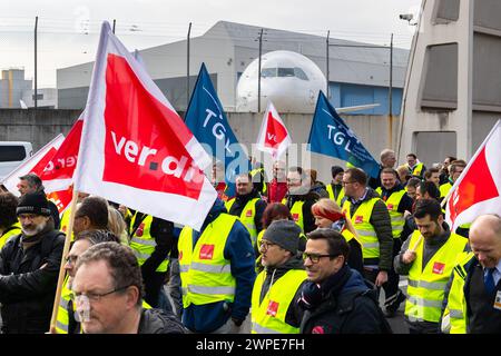 07. März 2024, Hessen, Frankfurt/Main: Ein Protestzug von Streikenden marschiert vom Lufthansa Aviation Center zum Terminal 1 mit Bannern und Verdi-Fahnen. Im Hintergrund ist ein Flugzeug der Lufthansa zu sehen. Mit erneuten Warnstreiks mehrerer Berufsgruppen lähmt die Verdi union am Donnerstag und Freitag wichtige Teile des deutschen Luftverkehrs. Foto: Lando Hass/dpa Stockfoto