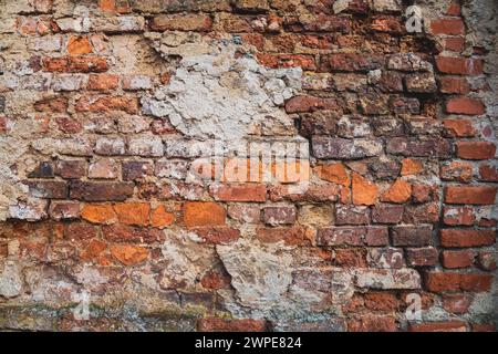 Verwitterte Ziegelwand mit abblätterndem Farbhintergrund Stockfoto