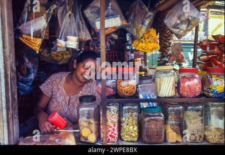 Sri Lanka, Minipe-Region; Frau in einem kleinen Geschäft verkauft Süßigkeiten und verschiedene Süßigkeiten. Stockfoto