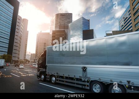 Gütertransporter mit leichten Bewegungsunschärfen, der zwischen Hochhäusern durch eine moderne Stadt fährt Stockfoto