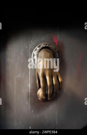 Vorderansicht des antiken Handklopfers Bronze Metall gegen Holztür mit roter Farbe Stockfoto