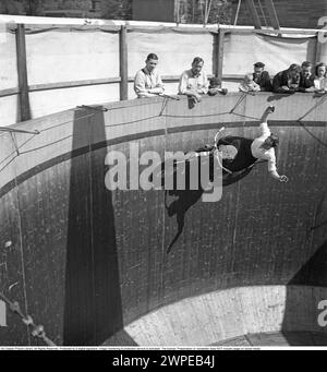 Mauer des Todes 1949. Die Mauer des Todes, das Motordrome, das Velodrome oder der Brunnen des Todes ist eine Nebenausstellung des Karnevals mit einem silos- oder tonnenförmigen Holzzylinder mit einem Durchmesser von normalerweise 6,1 bis 11,0 m (20 bis 36 Fuß) und aus Holzdielen, in der Motorradfahrer entlang der vertikalen Wand fahren und Stunts durchführen. durch Reibung und Zentrifugalkraft gehalten. Die ursprüngliche Mauer des Todes befand sich 1911 auf Coney Island in den Vereinigten Staaten. Ich habe mir einen Motorradfahrer in hoher Geschwindigkeit im Velodrome vorgestellt, der mit den Händen in der Luft zeigte, nicht wie er sollte am Lenker. Schweden 1949. Conard Stockfoto