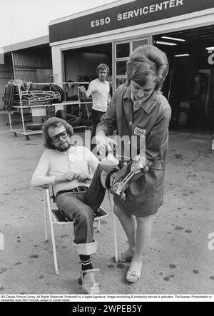 Rollschuhe 1972. Ein Mann auf Rollschuhen wird an einer Esso-Tankstelle gesehen, wie seine Räder geschmiert werden. Eine Frau des Personals wird mit einer Ölkanne gesehen, die die Räder schmiert. Schweden 1972. Stockfoto