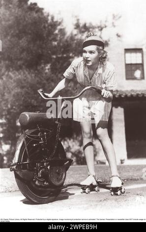 In den 1930er Jahren Eine Frau auf Rollschuhen hält sich am Lenker eines einrädrigen Motorrads, das sie nach vorne zieht. Sie sieht konzentriert aus, wenn die Geschwindigkeit zunimmt. Stockfoto