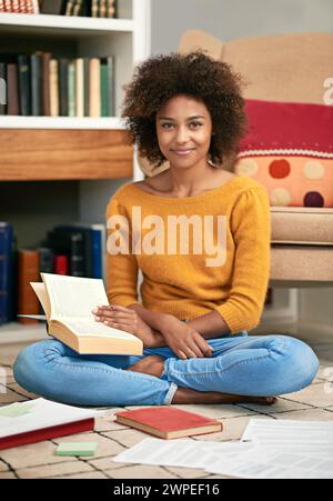 Porträt, Lächeln und glücklicher Schüler in der Bibliothek zu Hause, auf dem Boden und beim Lernen für die Prüfung. Ausbildung, Test und Lernen für Hochschulwissenschaftlerin in London Stockfoto