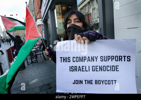 Ein Demonstrant steht vor Pret A Krippe mit einer palästinensischen Flagge und einem Plakat mit der Aufschrift "diese Kompanie unterstützt den israelischen Völkermord, tritt dem Boykott bei" während einer Demonstration. Demonstranten fordern, dass die Leute Costa Coffee boykottieren. Ihre Muttergesellschaft Coca-Cola betreibt eine Fabrik in der illegalen israelischen Siedlung Atarot in dem Gebiet, das von den Demonstranten als Palästina besetzt angesehen wird. Die Boykott Divestment and Sanctions (BDS)-Bewegung arbeitet daran, die internationale Unterstützung für Israels Unterdrückung der Palästinenser zu beenden und Israel unter Druck zu setzen, sich an das Völkerrecht zu halten, und hat eine Liste von Unternehmen zusammengestellt Stockfoto