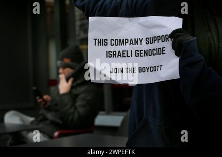 Ein Demonstrant steht vor Pret A Manger mit einem Plakat mit der Aufschrift "diese Firma unterstützt israelischen Völkermord, tritt dem Boykott bei" während einer Demonstration. Demonstranten fordern, dass die Leute Costa Coffee boykottieren. Ihre Muttergesellschaft Coca-Cola betreibt eine Fabrik in der illegalen israelischen Siedlung Atarot in dem Gebiet, das von den Demonstranten als Palästina besetzt angesehen wird. Die Boykott-Desinvestitions- und Sanktionsbewegung (BDS) arbeitet daran, die internationale Unterstützung für Israels Unterdrückung der Palästinenser zu beenden und Israel unter Druck zu setzen, das Völkerrecht einzuhalten, und hat eine Liste von Unternehmen zusammengestellt, die die Menschen sollten Stockfoto