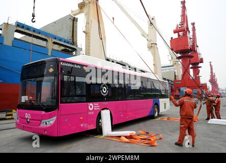 QINGDAO, CHINA - 7. MÄRZ 2024 - Arbeiter heben einen Bus im Hafen Qingdao in der ostchinesischen Provinz Shandong, 7. März 2024. Am selben Tag 53 inländische Neuheiten Stockfoto