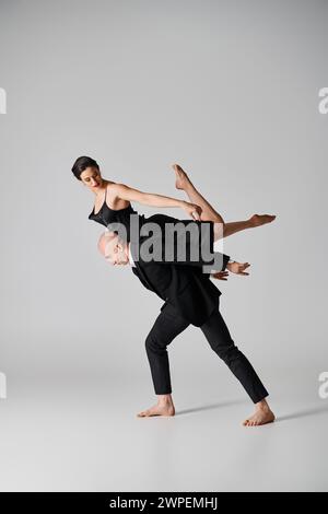 Anmutiger Tanz, ein junges Paar, das eine akrobatische Routine in einem Studio mit grauem Hintergrund aufführt Stockfoto