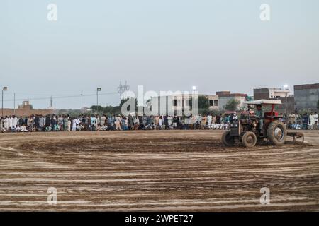 Pflügen mit Traktor auf Kabaddi-Boden. Der Traktorfahrer spielt mit einer Scheibenegge den Boden. Stockfoto