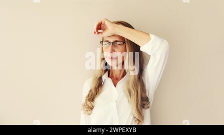 Erschöpfte, müde kaukasische Angestellte mittleren Alters mit Kopfschmerzen oder Schläfenschmerzen, leidet an Migräne, Verspannungen im Kopf zu Hause Stockfoto