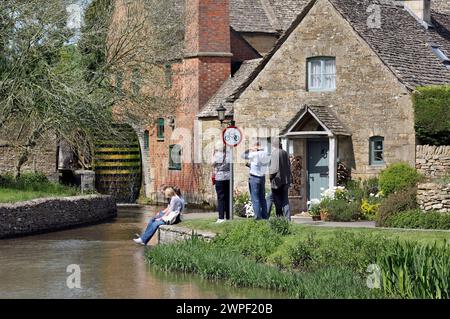 Besucher bewundern die Old Mill on the River Eye bei Lower Slaughter in den Cotswolds. Stockfoto