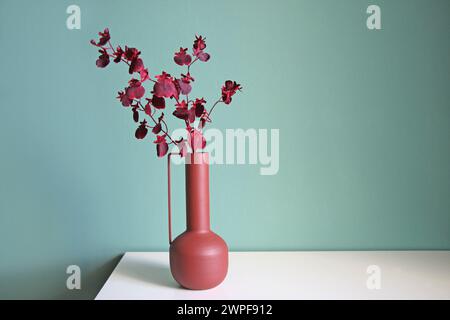 Blühender Zweig in einer modernen Keramikvase auf einem weißen Tisch. Orientalischer Stil. Platz für Ihren Text. Stockfoto