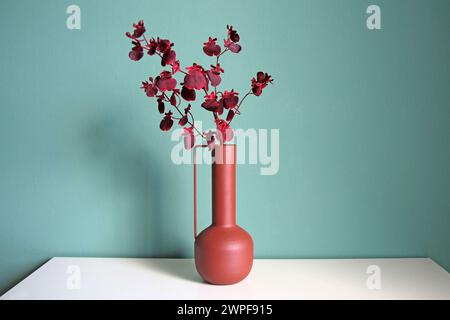 Blühender Zweig in einer modernen Keramikvase auf einem weißen Tisch. Orientalischer Stil. Platz für Ihren Text. Stockfoto