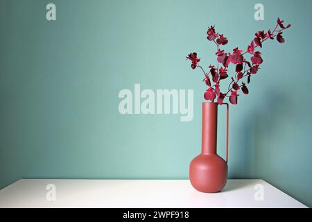 Blühender Zweig in einer modernen Keramikvase auf einem weißen Tisch. Orientalischer Stil. Platz für Ihren Text. Stockfoto