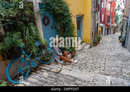 Stadtbild Grisia Straßenblick in Rovinj Kroatien mit gelben Häusern und blauen Türen und Fahrraddekoration mit einer Touristenfrau. Stockfoto