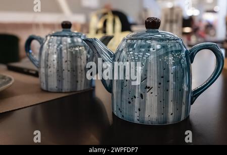 Teekanne mit einzigartigem und schönem Design für die Innendekoration. Blaue Keramik-Teekanne auf dem Tisch im Restaurant. Keramik-Teekanne in blauer Farbe. Nobod Stockfoto